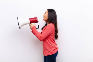 Genç, Latin, güzel bir kadın, düz duvara karşı megafonla.