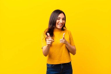 Genç, Latin, güzel bir kadın kendini mutlu, havalı, tatmin olmuş, rahat ve başarılı hissediyor, kameraya bakıyor, düz duvara karşı seni seçiyor.