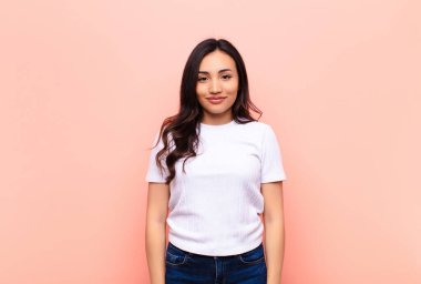 Genç, Latin, güzel bir kadın, pozitif ve kendinden emin gülümsüyor. Tatmin olmuş, arkadaş canlısı ve mutlu görünüyor.