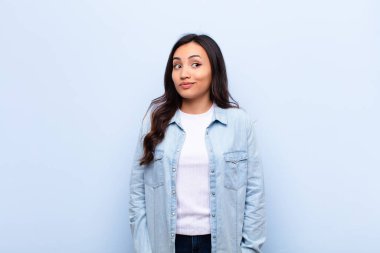 Genç, Latin, güzel bir kadın merak ediyor, mutlu düşünceler ve fikirler düşünüyor, hayal kuruyor, düz duvara karşı uzayı kopyalamaya çalışıyor.