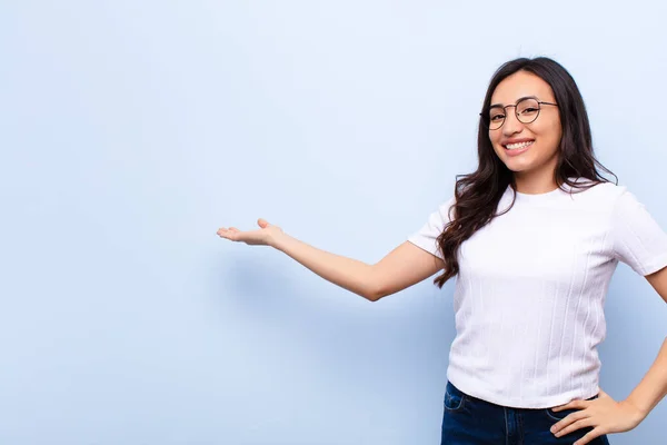 若いラテン語のきれいな女性は幸せと陽気 笑顔とあなたを歓迎し 平らな壁に対する友好的なジェスチャーであなたを招待します — ストック写真