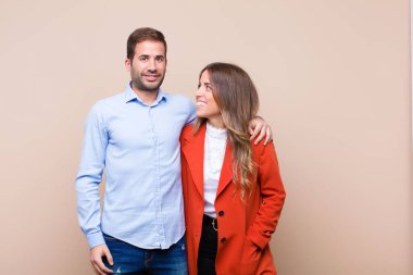 Genç ve güzel bir çift bej düz duvara karşı