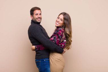 Genç ve güzel bir çift bej düz duvara karşı