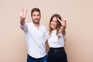 Genç ve güzel bir çift bej düz duvara karşı