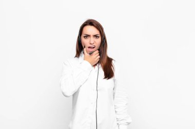 Ağzı ve gözleri açık, eli çenesinde genç ve güzel bir kadın. Hoş olmayan bir şok geçiriyor. Kulaklıklar ve mikrofonla ne söylüyor?