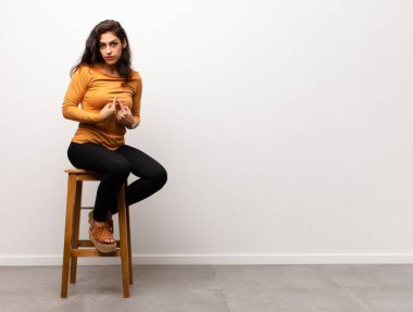 Genç ve güzel bir kadın gergin ve umutlu, dua ediyor ve bir odada iyi şanslar diliyor.