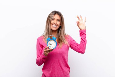 Genç, güzel bir kadın kendini mutlu, rahat ve tatmin olmuş hissediyor. Güzel bir jestle onaylıyor. Elinde çalar saatle gülümsüyor..