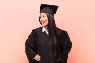 Genç Latin kız öğrenci mutlu, neşeli ve kendinden emin görünüyor, gururla gülümsüyor ve iki elini de kalçasında istiyor.