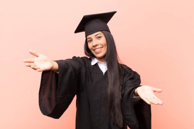 Genç Latin bayan öğrenci neşeyle gülümsüyor sıcak, dostça, sevgi dolu bir kucaklama yapıyor, mutlu ve sevimli hissediyor.