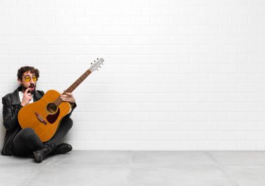 Genç müzisyen şaşırmış, gergin, endişeli ya da korkmuş bakışlarıyla, bir gitar, rock 'n roll konseptiyle fotokopi alanına doğru bakıyor.