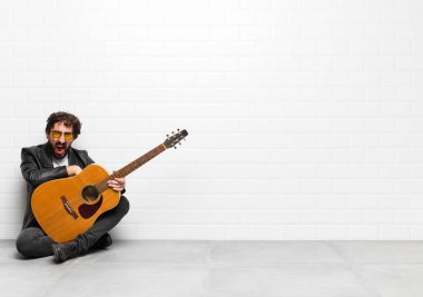 Genç müzisyen şok olmuş, kızgın, sinirli ya da hayal kırıklığına uğramış, ağzı açık ve öfkeli bir şekilde gitar, rock 'n roll konseptine bakıyor.