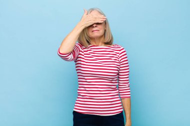 Yaşlı ya da orta yaşlı güzel bir kadın tek eliyle gözlerini kapatıyor korkmuş ya da endişeli, merak ediyor ya da körü körüne bir sürpriz bekliyor.