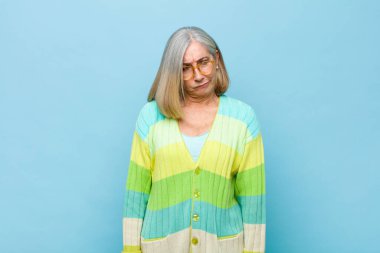 Yaşlı ya da orta yaşlı güzel bir kadın üzgün, üzgün ya da kızgın ve olumsuz bir tavır takınıyor, anlaşmazlık içinde kaşlarını çatıyor.