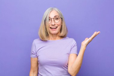 Yaşlı ya da orta yaşlı güzel bir kadın mutlu, şaşırmış ve neşeli, pozitif bir tavırla gülümseyen, bir çözüm ya da fikir gerçekleştiren.