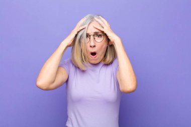 Yaşlı ya da orta yaşlı, güzel bir kadın dehşete kapılmış ve şok olmuş hissediyor. Bir hata yüzünden ellerini kaldırıyor ve panikliyor.