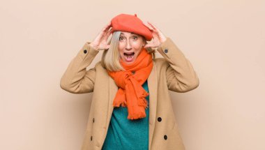 Yaşlı ya da orta yaşlı güzel bir kadın el ele tutuşuyor, ağzı açık, son derece şanslı, şaşırmış, heyecanlı ve mutlu hissediyor.