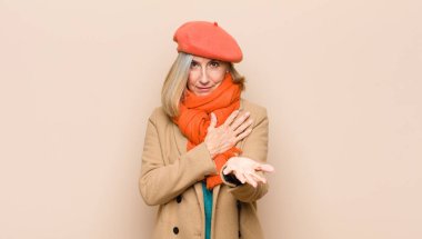 Yaşlı ya da orta yaşlı güzel bir kadın mutlu ve aşık, bir eli kalbinin yanında ve diğer eli önde uzanmış şekilde gülümsüyor.