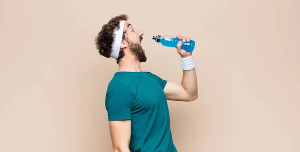 Jonge Sportman Met Een Energy Drink Fles Tegen Platte Wand — Stockfoto