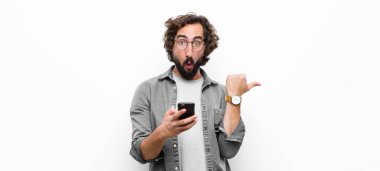 Genç çılgın adam akıllı telefonunu beyaz duvara karşı kullanıyor.