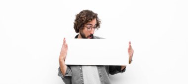 Genç, çılgın, havalı adam beyaz duvara karşı bir pankart tutuyor.