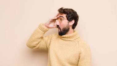 Genç havalı adam mutlu, şaşkın ve şaşırmış görünüyor, gülümsüyor ve düz duvara karşı inanılmaz ve inanılmaz iyi haberler veriyor.