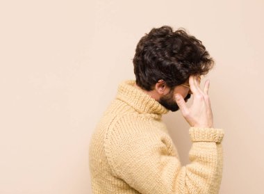 Stresli, yorgun ve hayal kırıklığına uğramış, alnından ter damlayan, umutsuz ve bitkin hisseden genç bir adam.