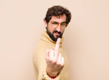 Genç, havalı bir adam sinirli, sinirli, asi ve agresif orta parmağını sallayarak düz duvara karşı savaşıyor.