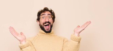 Genç havalı adam kendini mutlu ve başarılı hissediyor, gülümsüyor ve alkışlıyor, düz duvara karşı alkış ile tebrik ediyor.