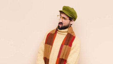 Genç sakallı adam şok olmuş, kızgın, sinirli ya da hayal kırıklığına uğramış, ağzı açık ve öfkeli görünüyor.