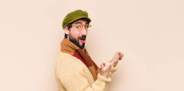 Genç, havalı sakallı, neşeli ve tesadüfen gülümseyen bir adam yan taraftaki fotokopi alanını gösteriyor, mutlu ve tatmin olmuş hissediyor.