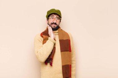 Genç, sakallı, yanak tutan ve acı veren diş ağrısı çeken hasta, mutsuz ve dişçi arayan bir adam.