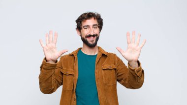 Genç yakışıklı adam gülümsüyor ve arkadaş canlısı görünüyor, onuncu ya da onuncu numarayı gösteriyor, eli önde, düz duvara doğru sayıyor.