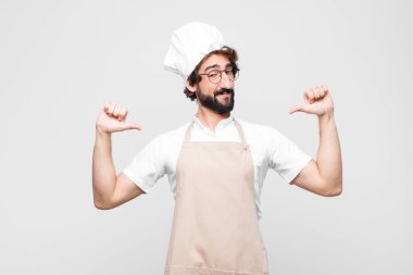 Genç çılgın şef kendini gururlu, kibirli ve kendinden emin hissediyor. Tatmin olmuş ve başarılı görünüyor. Kendini beyaz duvara gösteriyor.