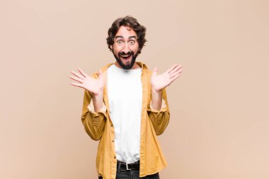 Genç çılgın havalı adam mutlu ve heyecanlı görünüyor. Beklenmedik bir sürprizle şoke oldu. İki eli de duvara dayalı.