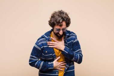 Genç, çılgın, havalı bir adam komik bir şakaya yüksek sesle gülüyor, mutlu ve neşeli hissediyor, düz duvara karşı eğleniyor.