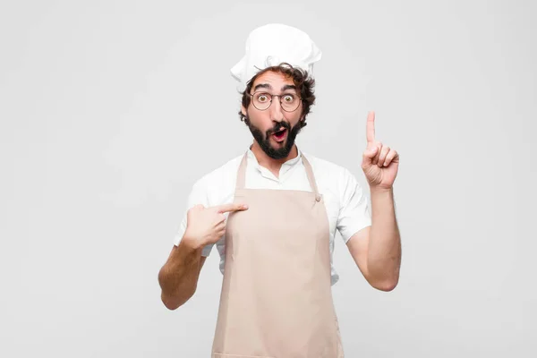 年轻的疯狂厨师感到自豪和惊讶 自信地指点着自己 觉得自己是白墙上最成功的厨师 — 图库照片