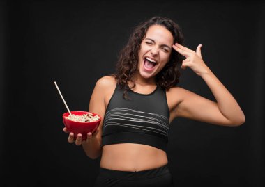 Genç ve güzel bir kadın mutsuz ve stresli görünüyor, intihar jesti silahla işaret ediyor, kafasına doğru işaret ediyor sağlıklı bir kase yiyor.