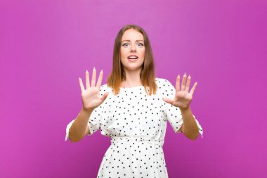 Kızıl saçlı güzel bir kadın sersemlemiş ve korkmuş hissediyor, korkunç bir şeyden korkuyor, elleri açık, mor duvardan uzak durun diyor.