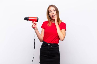 Kızıl saçlı güzel bir kadın şok olmuş ve korkmuş hissediyor, ağzı açık ve elleri yanaklarında kuaför tutarken korkmuş görünüyor.