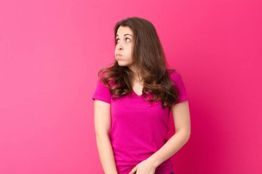 Aptal, çılgın, şaşırmış bir ifadeyle genç, güzel bir kadın. Yanakları şişmiş, içi doldurulmuş, şişman ve pembe duvarda yemek dolu.