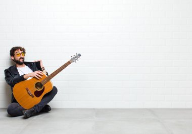 Gitarlı genç adam odada yerde yatıyor.