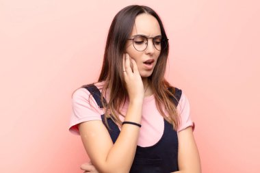 Genç, güzel bir kadın, yanağını tutuyor ve ağrılı diş ağrısı çekiyor. Hasta, sefil ve mutsuz hissediyor. Pembe duvarda bir dişçi arıyor.