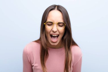 Genç ve güzel bir kadın agresif bir şekilde bağırıyor. Kızgın, sinirli, öfkeli ya da sinirli görünüyor. Mavi duvara karşı hayır diye bağırıyor.