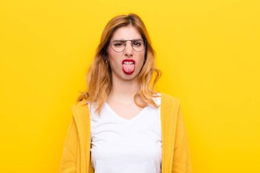 Genç, güzel sarışın kadın iğreniyor ve rahatsız oluyor. Dilini dışarı çıkarıyor. Çirkin bir şeyden hoşlanmıyor ve sarı duvara karşı iğreniyor.