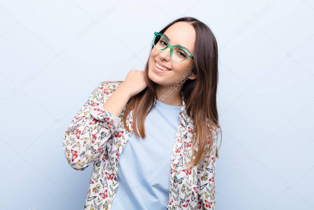 young pretty woman laughing cheerfully and confidently with a casual, happy, friendly smile against blue wall