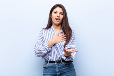 Genç ve güzel bir kadın mutlu ve aşık, bir eli kalbinin yanında gülümsüyor ve diğer eli önde uzanıyor.