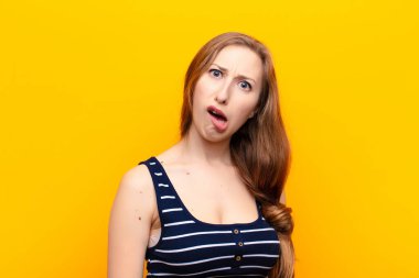 yound blonde woman feeling puzzled and confused, with a dumb, stunned expression looking at something unexpected