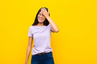 Genç ve güzel Latin kadın gülüyor ve alnına şaplak atıyor. Unuttum yoksa düz duvara karşı yaptığım aptalca bir hataydı. 