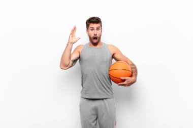 Genç yakışıklı adam elleri havada bağırıyor, öfkeli, sinirli, stresli ve üzgün hissediyor elinde bir basketbol topu tutuyor..