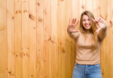 Genç sarışın kadın gülümsüyor ve arkadaş canlısı görünüyor, 7 ya da 7 numarayı gösteriyor, eli önde, geriye doğru sayıyor.